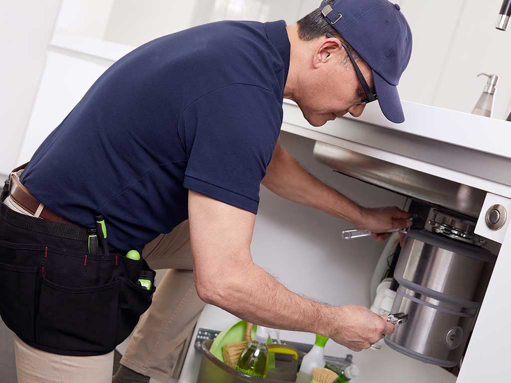 Technician fixing a garbage disposal