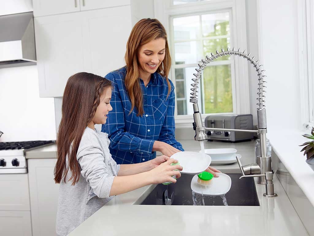 Mom and daughter at kitchen sink washing dishes 