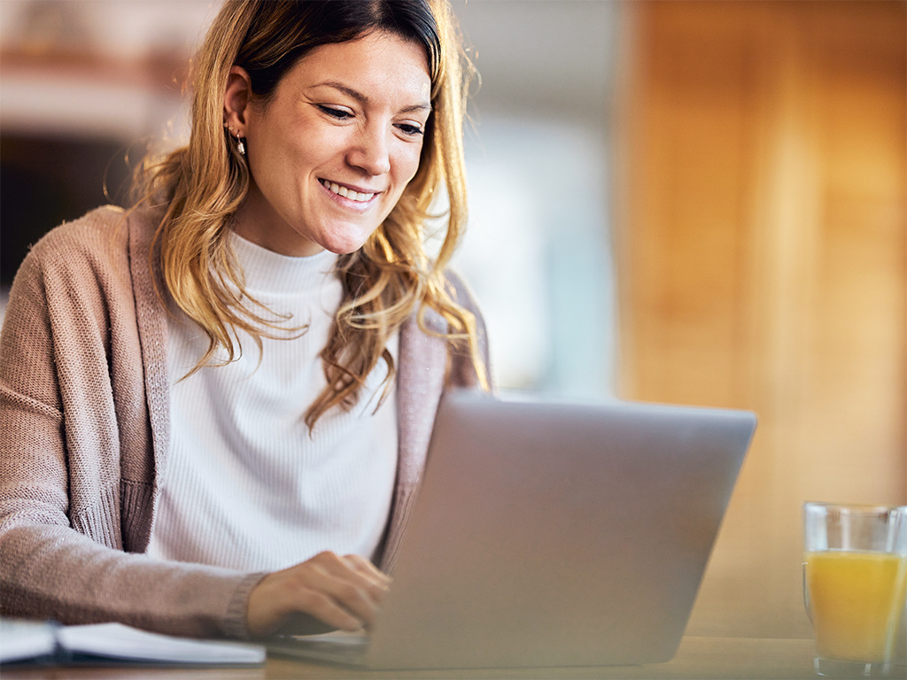 Woman smiling and typing on a laptop