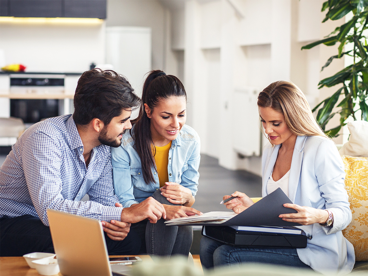 Young couple looking at files in a folder with agent