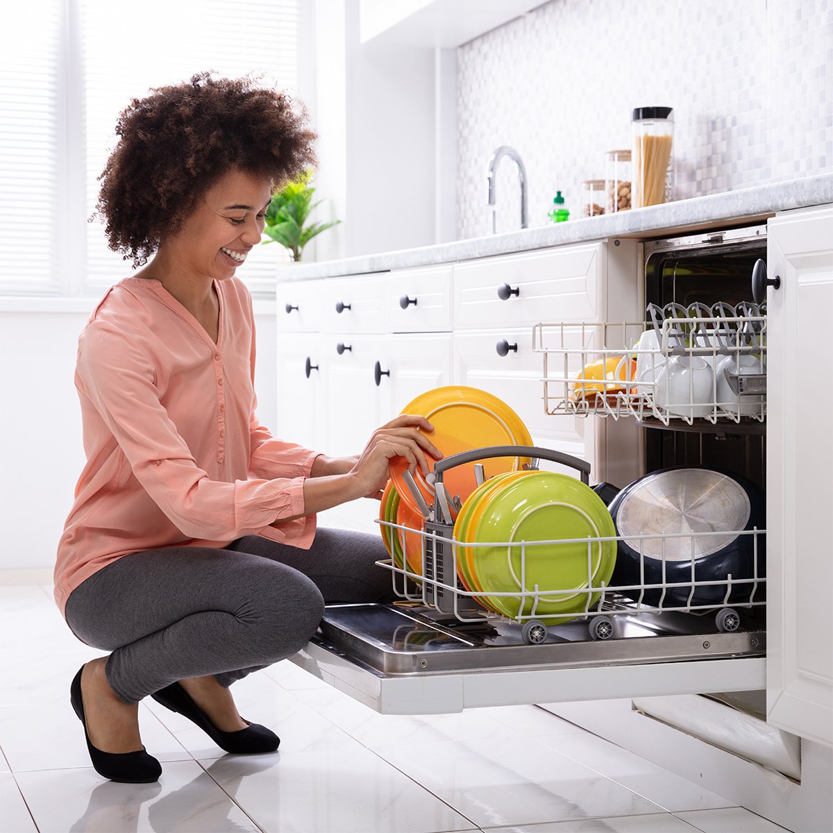 Woman kneeling to load dishwasher