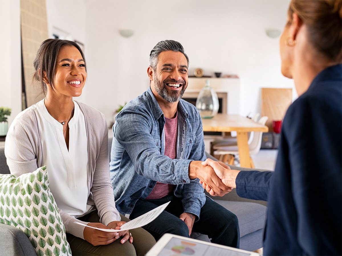 Couple on couch shaking hands with agent