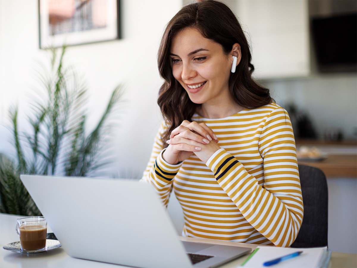 Woman looking at laptop with earbuds