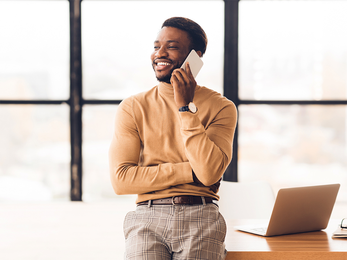 Man leaning on desk speaking into mobile phone