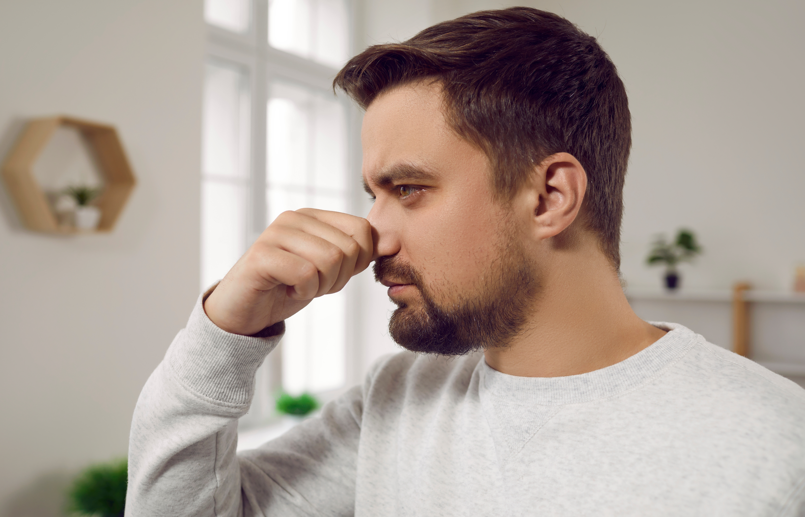 a man holding his nose because of a gas leak smell