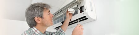 Man reaching up to fix his A/C unit