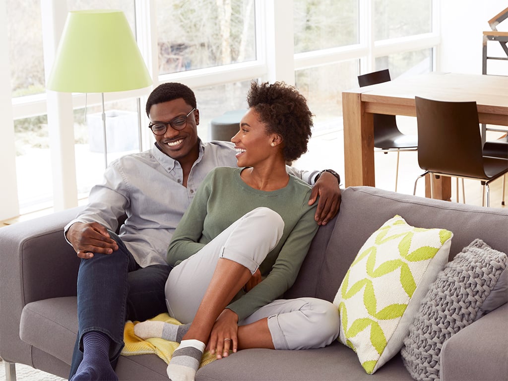 Couple cuddling on couch smiling at each other