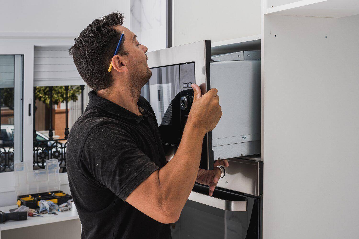 A home warranty service technician installing a new microwave