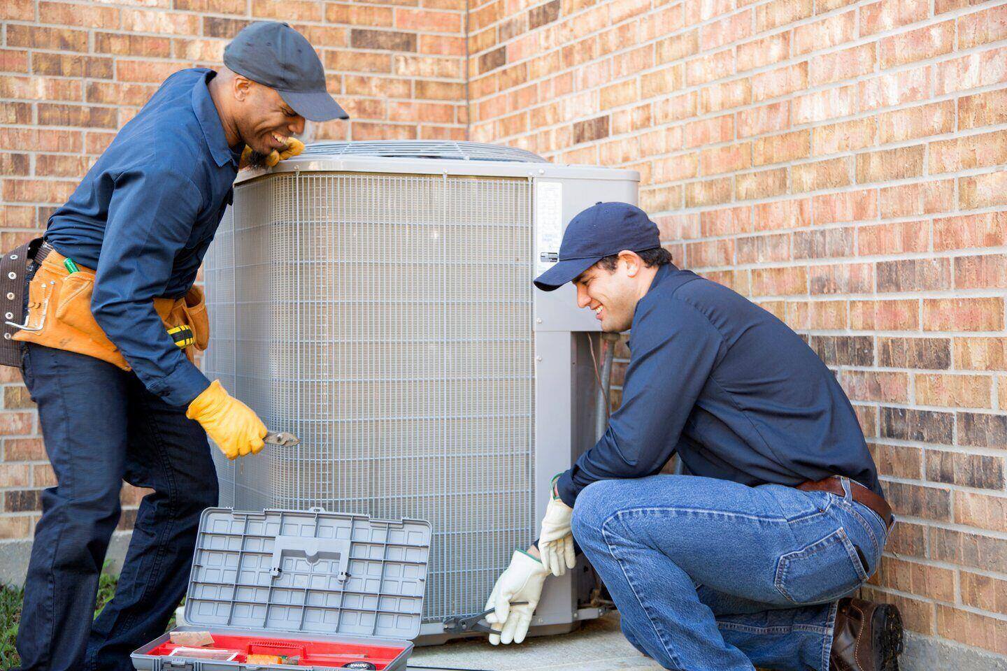 Two men working on an HVAC unit covered under home warranty