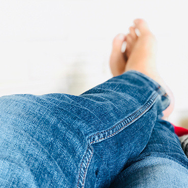 Down view of someone's bare feet and legs in jeans