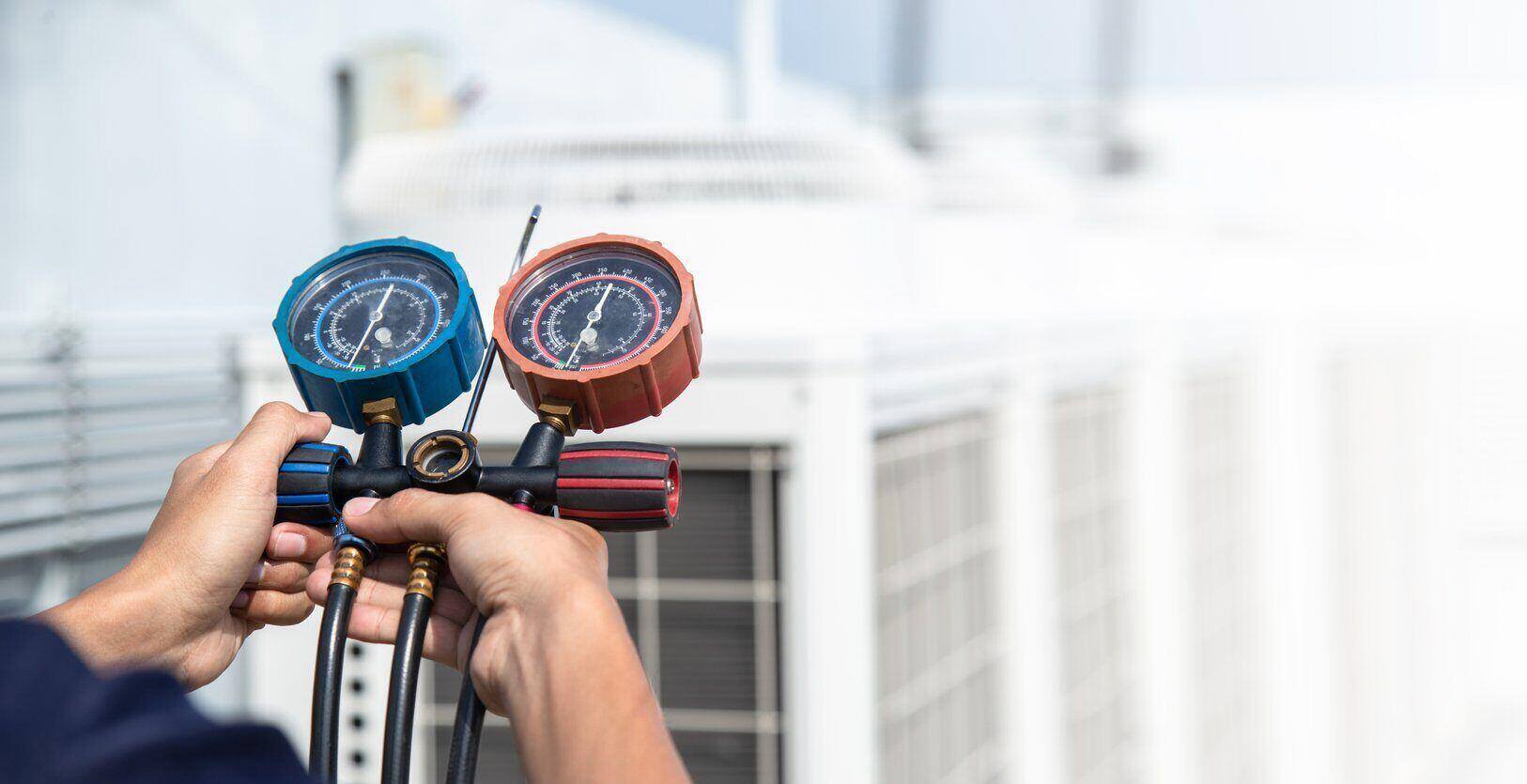 Repairman hands holding an air conditioner measuring gauge